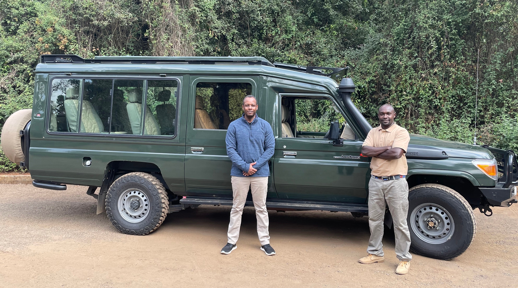 Head of Kararan Tours, Cyprian, and one Kararan's drivers, Sam, standing in front of one of our pop-up roof 4x4 Safari Landcruisers